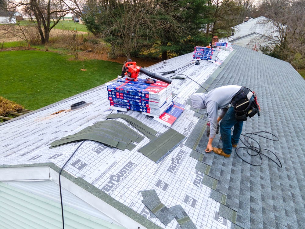 man with sweater working on house roof